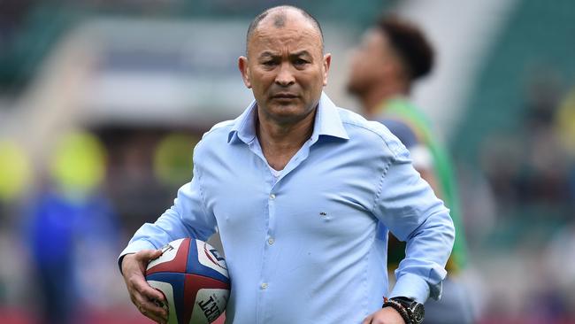 England coach Eddie Jones carries a rugby ball as his players warm up.