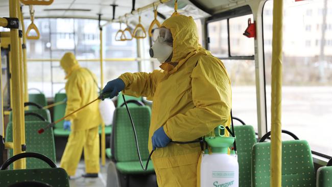 Employees wearing protective gear spray disinfectant to sanitise a passenger bus as a preventive measure against the coronavirus in Lviv, Ukraine. Photo: AP Photo/Mykola Tys