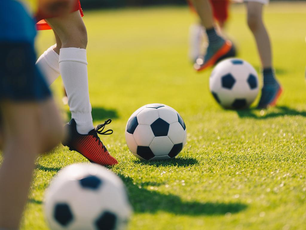 Soccer Football Training for Children. Kids Playing Soccer on Training Football Pitch. Beginner Soccer Drills for Kids. Coach in the Background Coaching Youth Soccer