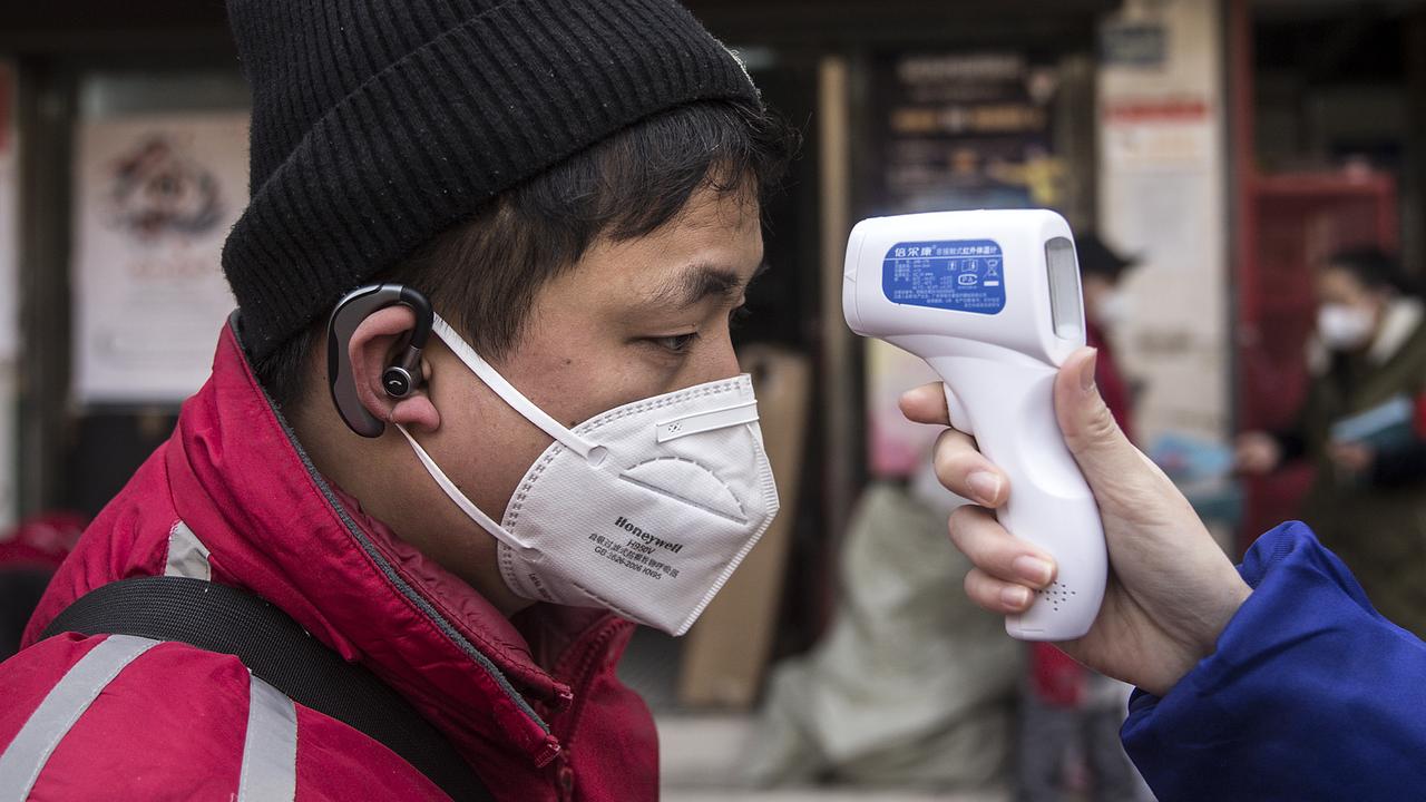 A community worker checks the temperature of courier in Wuhan. Picture: Getty Images