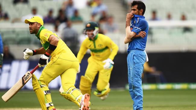 India's Yuzvendra Chahal (R) looks on as Australia's Glenn Maxwell (L) and Australia's Peter Handscomb take a run during the third one-day international cricket match between Australia and India at the Melbourne Cricket Ground in Melbourne on January 18, 2019. (Photo by Jewel SAMAD / AFP) / -- IMAGE RESTRICTED TO EDITORIAL USE - STRICTLY NO COMMERCIAL USE --