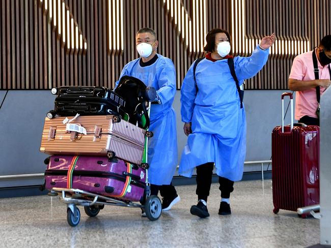 International travellers wearing personal protective equipment (PPE) arrive at Melbourne's Tullamarine Airport on November 29, 2021 as Australia records it's first cases of the Omicron variant of Covid-19. Photo by William WEST / AFP