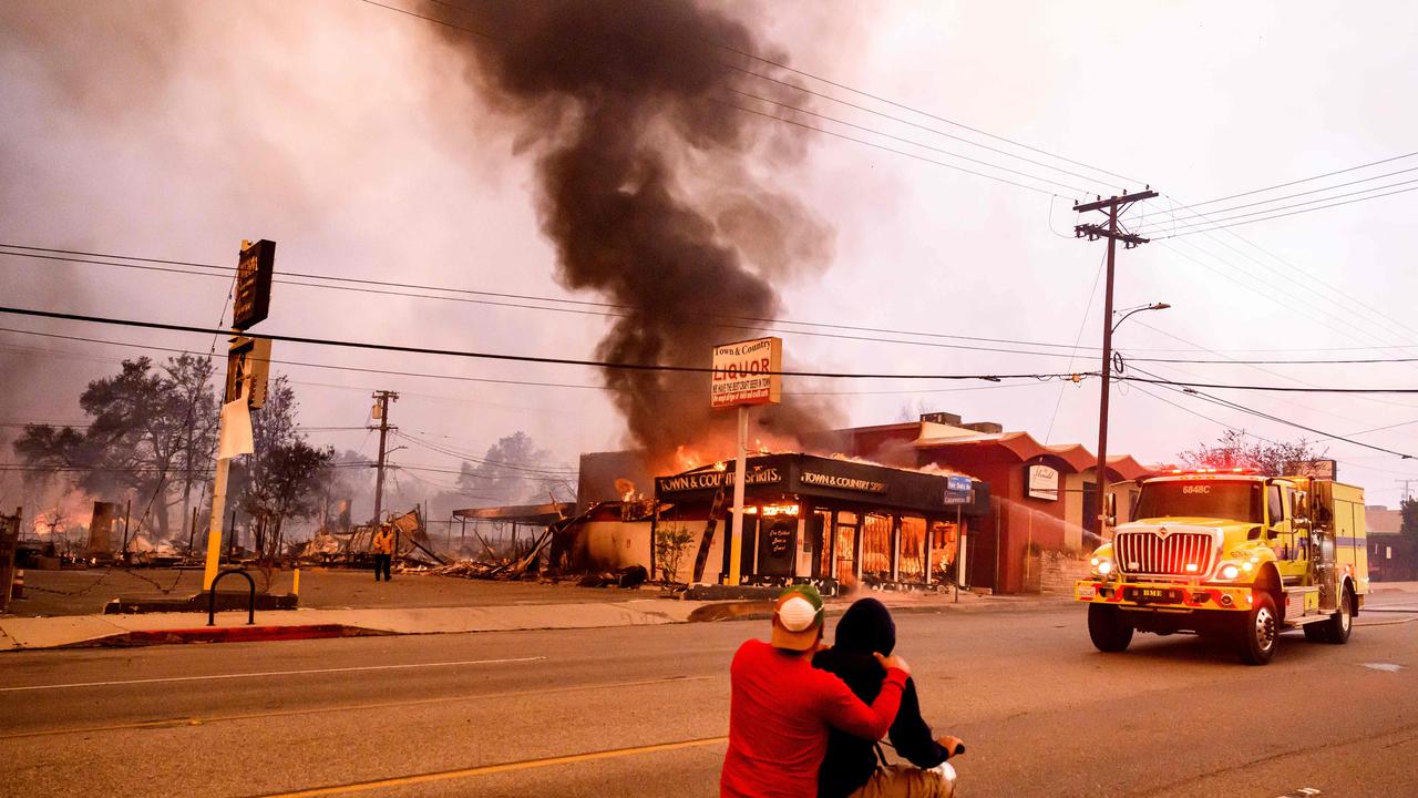 Residents ride their motorbike past a burning liquor store during the Eaton fire in the Altadena area of Los Angeles County. Picture: Josh Edelson/AFP