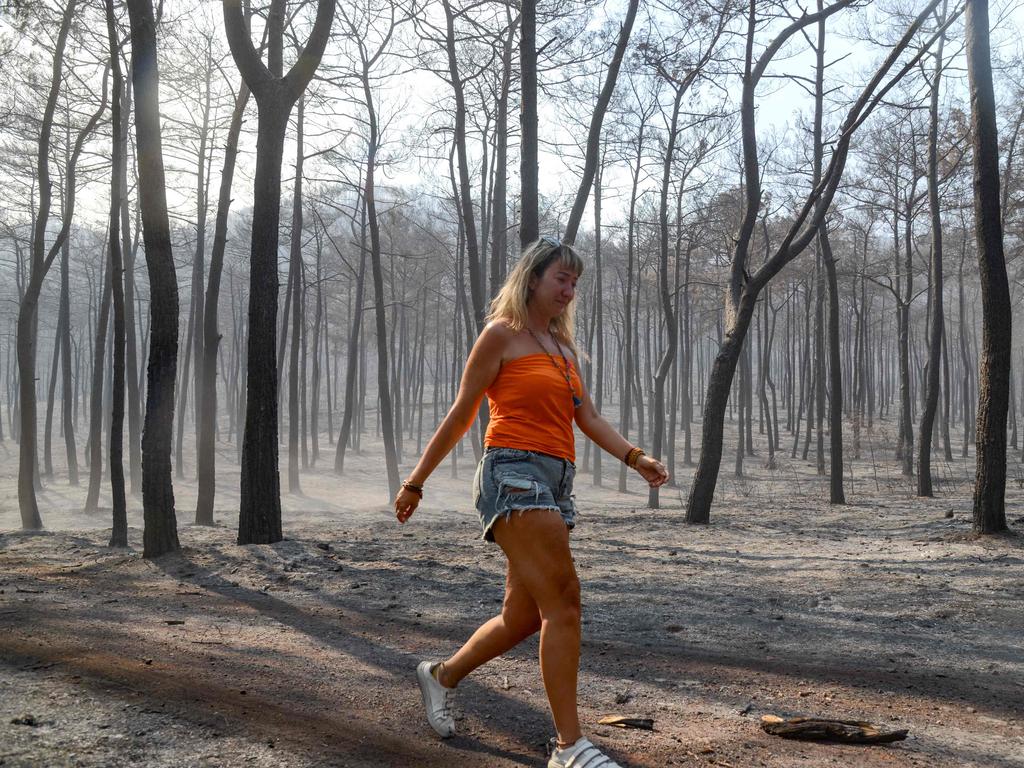 A woman walks through a burned forest as a massive wildfire in Turkey. Picture: Ilyas Akengin/AFP