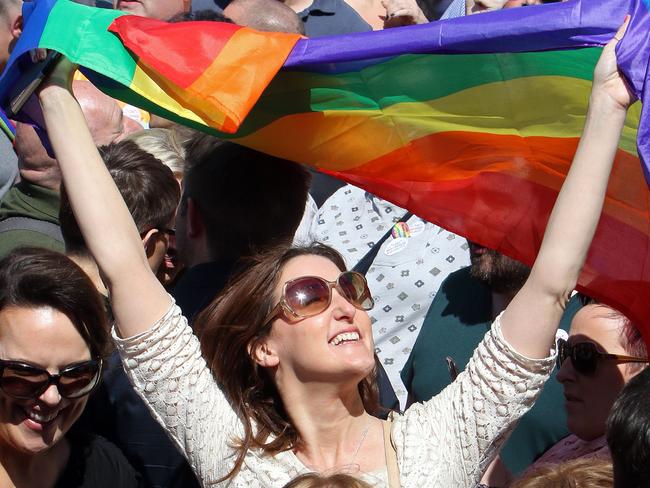 A woman holds up the rainbow flag, a gay pride flag, as thousands of people gather at Belfast city hall, at a rally for gay marriage rights on June 13, 2015 following the Yes vote in last month's Irish referendum on gay marriage. Northern Ireland will soon be the only part of the UK or Ireland where gay marriage is denied. AFP PHOTO / PAUL FAITH