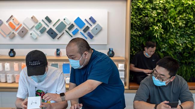 A store representative helping customers at an Apple Store in Beijing. Picture: Nicolas Asfouri/AFP