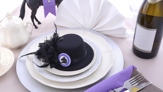 Melbourne cup generic, Horse racing Ladies Luncheon fine dining table setting with small black fascinator hat, decorations and champagne.