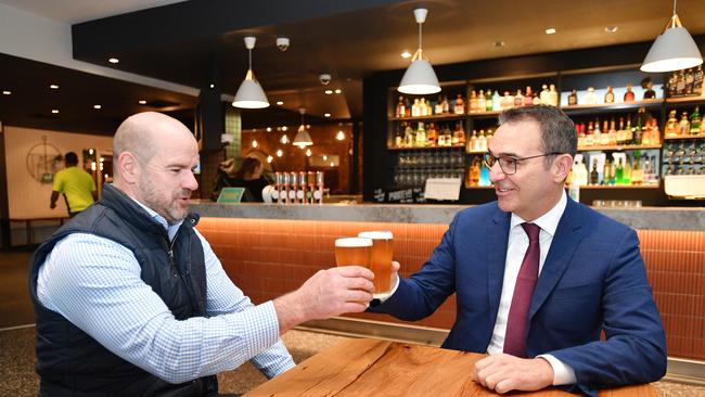 Premier Steven Marshall and former AFL player Mark Ricciuto enjoy a drink sitting down at the Alma Hotel. After midnight Friday they will be able to stand up outside to have a beer. Picture: AAP Image/David Mariuz