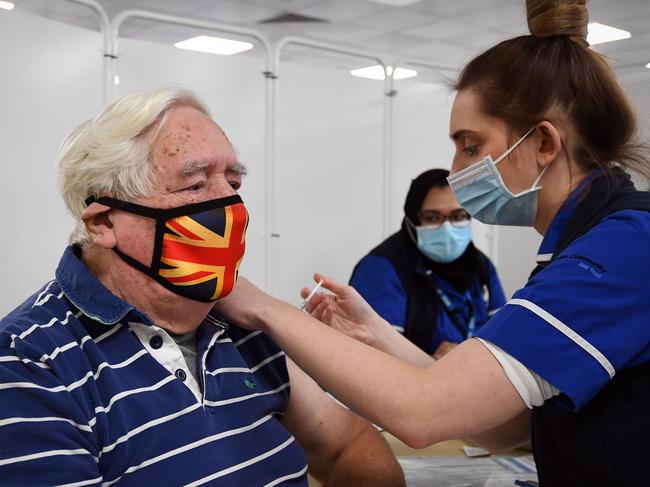 Robert Williams, 84, receives an injection of the Oxford/AstraZeneca Covid-19 vaccine at a mass vaccination centre at Epsom Downs Racecourse in Epsom, southern England on January 11, 2021. - Seven mass coronavirus vaccination sites opened across England on Monday as the government races to dose millions of people while a new strain of the disease runs rampant across the country. The sites include football stadiums and a horse racing course, and are located in cities including Bristol, London, Newcastle and Manchester. (Photo by Joe Giddens / POOL / AFP)