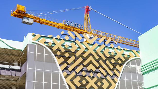 A crane does the finishing touches to the facade of the building. Picture: Richard Walker