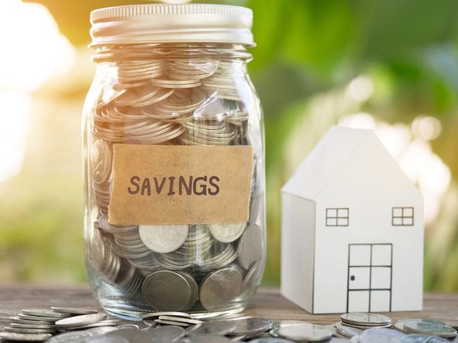 Full of coins in glass jar with savings tap and house model in background for property business concept. Australian money generic savings, housing, mortgage