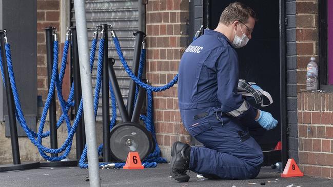 A forensic officer kneels to gather evidence at the scene of the shooting. Picture: AAP Image/Ellen Smith