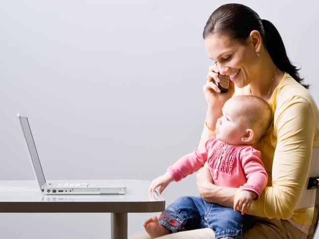 Working mother holding baby while talking on cell phone at desk. Child. Mobile phone. Woman. Generic image. Thinkstock.