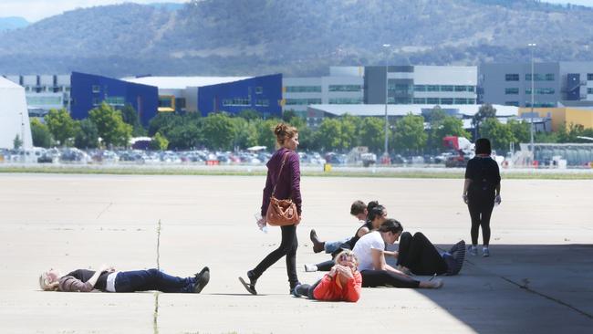 Stranded passengers sit and wait on a military tarmac in Canberra. Picture: Gary Ramage