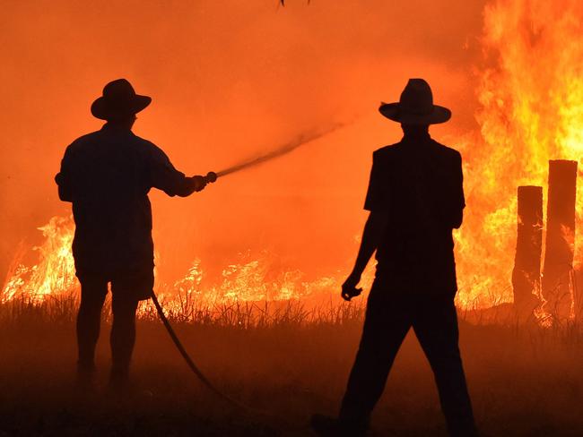 (FILES) Residents defend a property from a bushfire at Hillsville near Taree, 350km north of Sydney on November 12, 2019. Australian firefighters are preparing what they predict will be the fiercest fire season since the monster "Black Summer" blazes of 2019-2020. However, some warn that these brave volunteers may one day be unable to cope if global warming leads to raging fires, storms, and floods of ever-increasing intensity. (Photo by PETER PARKS / AFP) / To go with AFP story Australia-environment-climate-fire,FOCUS by Sharon Marris and Andrew Leeson