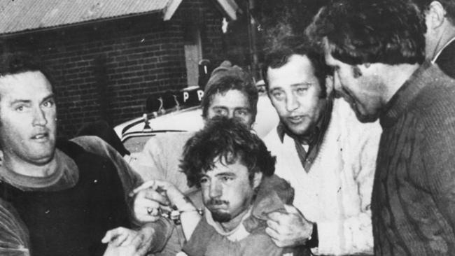 Edward ‘Jockey’ Smith (centre) being escorted by detectives into the Nowra police station after a dramatic manhunt in 1977.