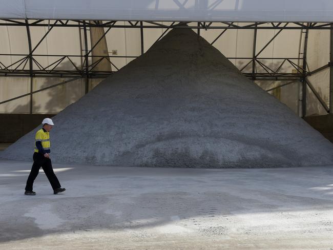 A worker walks past a pile of lithium ore at a Talison Lithium Ltd. site, a joint venture between Tianqi Lithium Corp. and Albemarle Corp., in Greenbushes, Australia, on Thursday, Aug. 3, 2017. Rising Chinese demand for lithium-ion batteries needed for electric vehicles and energy storage is driving significant price gains and an asset boom in Australia, already the world's largest lithium producer. Photographer: Carla Gottgens/Bloomberg