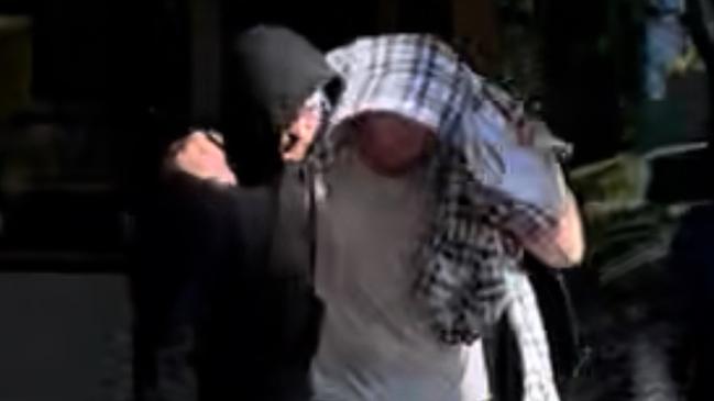 Nathan Bernhard leaving Nowra Police Station, hidden under blanket. Picture: Tom McGann
