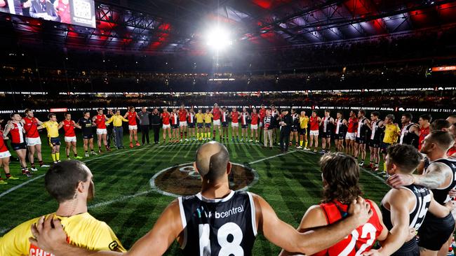 MELBOURNE, AUSTRALIA - JUNE 17: Players, coaches and umpires huddle as Tim Watson and Nathan Burke speak before Spuds Game during the 2022 AFL Round 14 match between the St Kilda Saints and the Essendon Bombers at Marvel Stadium on June 17, 2022 in Melbourne, Australia. (Photo by Michael Willson/AFL Photos via Getty Images)