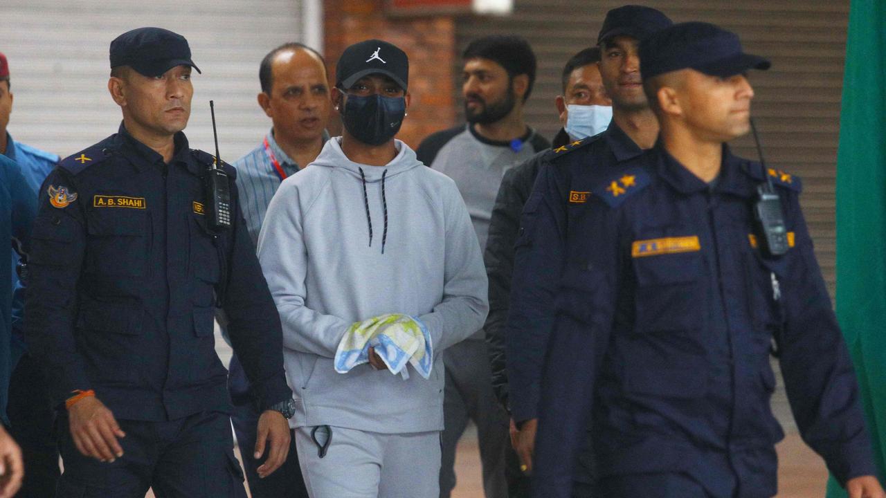 Nepali cricketer Sandeep Lamichhane is escorted by police after being taken into custody to face rape charges. Photo by Barsha SHAH / AFP