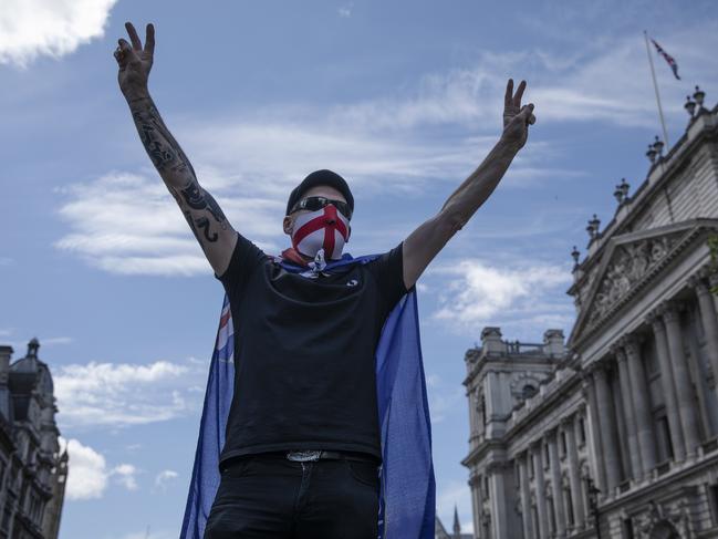 A far-right protester wearing a St George's Cross face mask climbs on a barrier as far-right linked groups gather around London’s statues. Picture: Getty