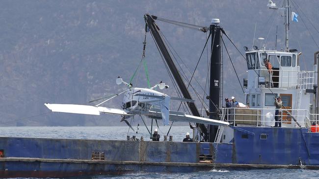 Plane removed from water with crane on barge, "Kalunda" as members of Tasmania Police photograph it. The plane crashed into the sea off the Tasman Peninsula with a pilot and photographer on board. They were covering the Sydney to Hobart Yacht Race. Picture: LUKE BOWDEN