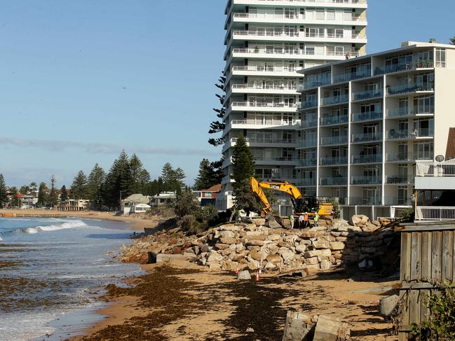 A ramp is being built on the beach near the damaged houses in Collaroy. The ramp will be used to get machines and equipment down on the beach, so the work can start around the affected homes. The ramp is expected to finish on Friday. Engineers and contractors walking around the ramp.