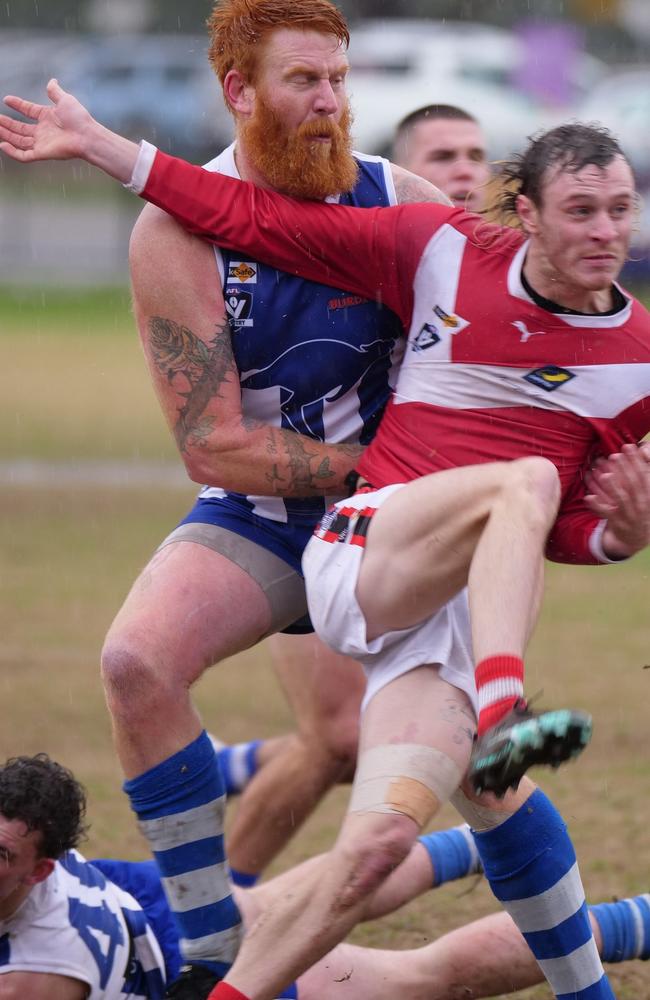 Jonno Ross gets a kick away as he’s tackled by Langwarrin ruckman Matthew Naughton. Picture: Paul Churcher