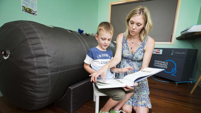 Eli Campbell reads a book with mum Brittany Cervantes before a session in his portable hyperbaric chamber. Picture: Lachie Millard