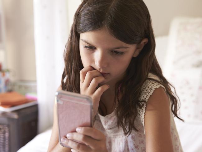 Young Girl In Bedroom Worried By Bullying Text Message