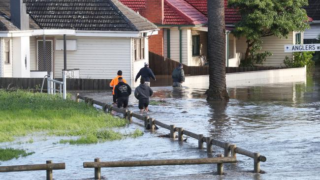 People wade through floodwaters on Anglers Way, Maribyrnong. Picture: David Crosling