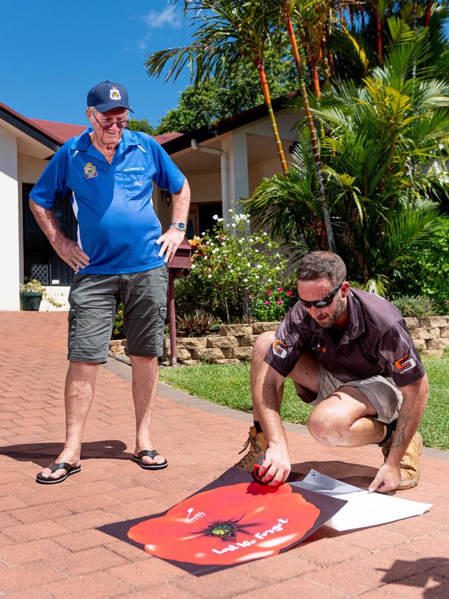 Zac Kirsopp from Sign City (right) installs a poppy on the driveway of Palmerston RSL president Bill Simpkins' home. Picture: Che Chorley