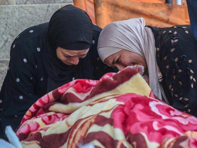 KHAN YUNIS, GAZA - DECEMBER 12: (EDITOR'S NOTE: Image depicts death) Two women cry as they mourn while collecting the bodies of Palestinians killed in an airstrike on December 12, 2023 in Khan Yunis, Gaza. World Health Organisation's Executive Board adopted a rare resolution on access for life-saving aid into Gaza and respect for laws of war, with the UN health chief reiterating an immediate ceasefire as "nowhere and no one is safe" in Gaza. (Photo by Ahmad Hasaballah/Getty Images)