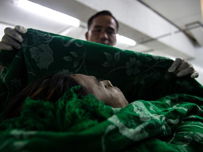 EDITORS NOTE: Graphic content / This picture taken on October 30, 2016 shows embalmer Alejandro Ormeneta displaying the body of an alleged drug dealer gunned down by unidentified men that he just finished embalming in the morgue of Veronica Memorial Chapel in Manila. Business has never been busier for undertaker Alejandro Ormeneta but, after five months on the frontlines of the Philippines' brutal drug war, he just wants the killings to stop. / AFP PHOTO / Noel CELIS / TO GO WITH Philippines-Duterte-drugs-crime-death,FOCUS by Ayee MACARAIG