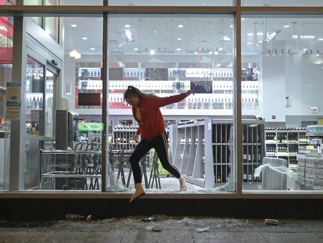 A woman jumps out of a Walgreens store empty-handed in Chicago, after seeing police officers nearby. Picture: John J. Kim/Chicago Tribune via AP