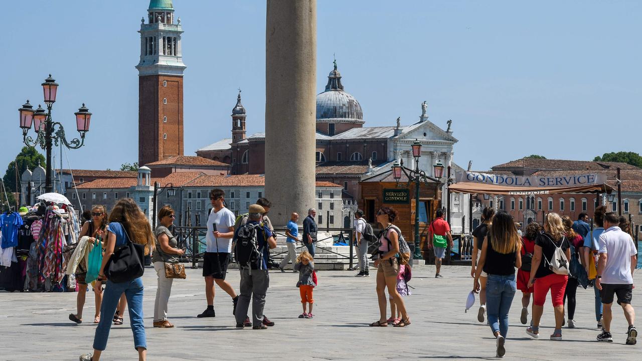 People walk across Piazza Riva degli Schiavoni with San Giorgio Maggiore church in background, on June 12, 2020 in Venice as the country eases its lockdown. (Photo by ANDREA PATTARO / AFP)