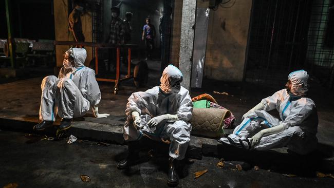 Volunteers rest after cremating the body of a monk suspected of dying of the Covid-19 in Taungoo district in Myanmar's Bago region. Picture: AFP