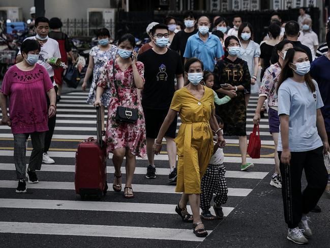 Residents wear face masks while crossing the street in Wuhan, China where the response level of public health emergencies has been reduced to level 3. Picture: Getty Images