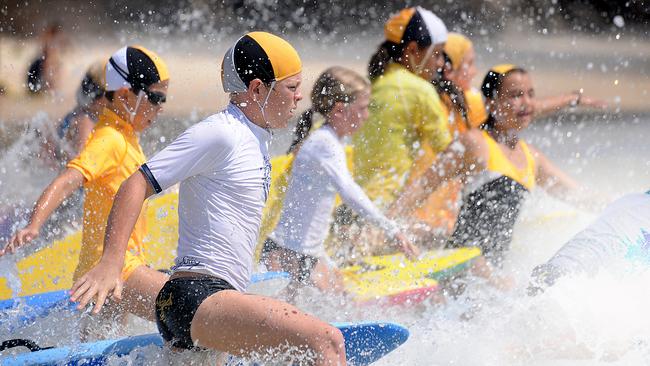 Rainbow Beach Surf Club nippers head out through the surf with their boards on the first weekend of their age championship surf sport competition.