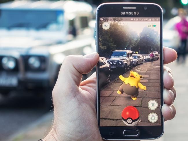 AUGMENTED REALITY Edinburgh, UK - July 18, 2016: Closeup of a man holding a Samsung S6 smartphone, playing Pokemon Go with the game's augmented reality superimposing a character onto the pavement surface, as a person approaches in the distance.  Image: iStock For Study Options 2017 feature