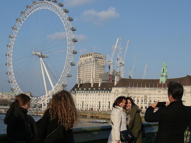 People pose on Westminster Bridge with the London Eye in the background in central London on March 23, 2017 after it reopened following the March 22 terror attack at the British parliament. Picture: AFP
