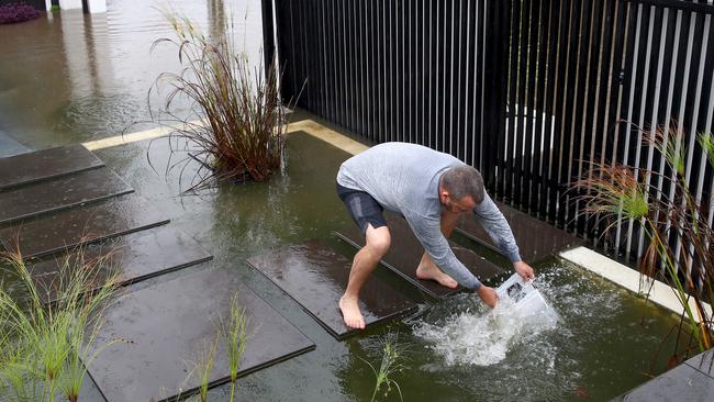 Jim Hetherington tries to rescue his goldfish from the front pond of his home in River Rd as rising floodwater threatens his home. Picture: Toby Zerna