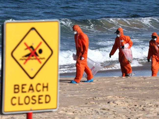 TOPSHOT - Workers in protective suits conduct a cleanup operation to clear petroleum-based "tar balls" washed ashore on Coogee Beach in Sydney on October 17, 2024. Lifeguards declared Sydney's famed Bondi beach and several other strands closed on October 17, as more mysterious black "tar ball" globules -- ranging from the size of peas to tennis balls -- washed up along the city's shores. Chemical testing has identified them as hydrocarbon-based tar balls, local officials said. (Photo by David GRAY / AFP)