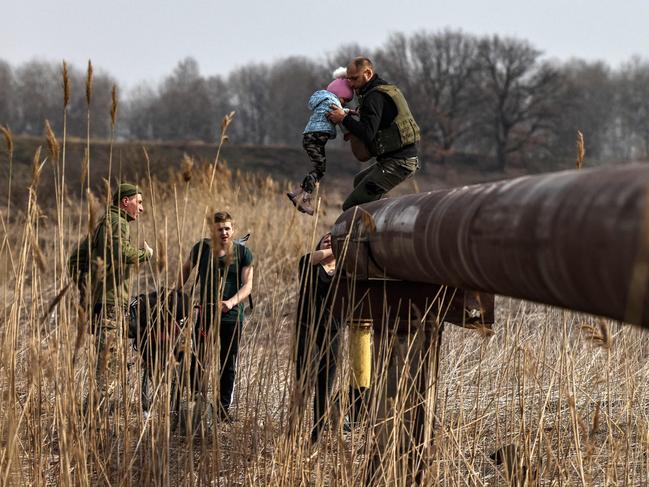 Ukrainian soldiers help a family cross a river on the outskirts of Kyiv. Picture: Ronaldo Schemidt/AFP