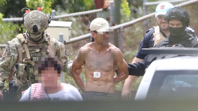 A man is led away from the siege house. Picture: Tara Croser