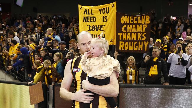 Jarryd Roughead of the Hawks carries his daughter Pippa through the banner.