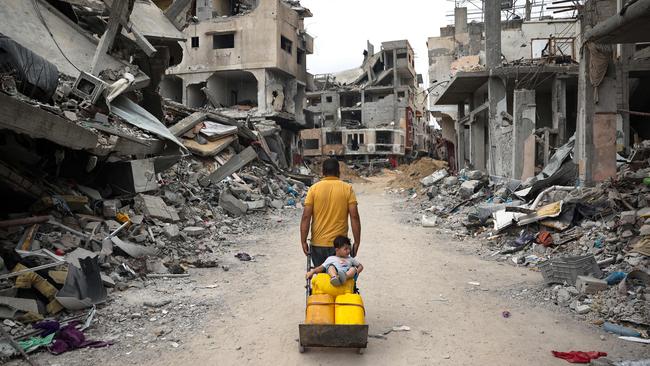 A Palestinian with child pulls a cart past destroyed buildings in Khan Younis. Picture: AFP