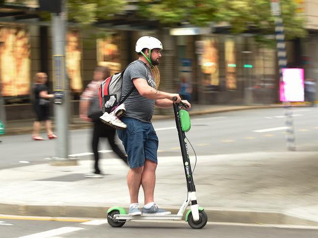 A Lime user crosses the street on a scooter in the Brisbane CBD. Picture: AAP Image/Albert Perez