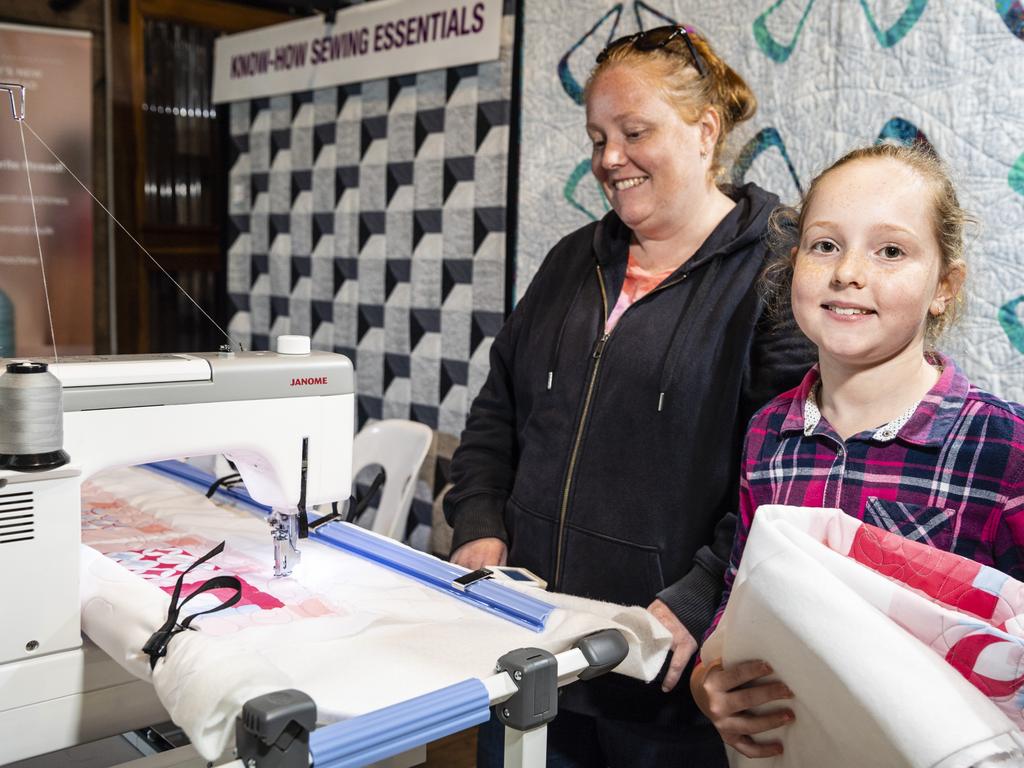 Lana Nash, with daughter Charlotte holding the quilt she stitched, uses a quilting machine at Craft Alive at the Goods Shed, Saturday, May 21, 2022. Picture: Kevin Farmer