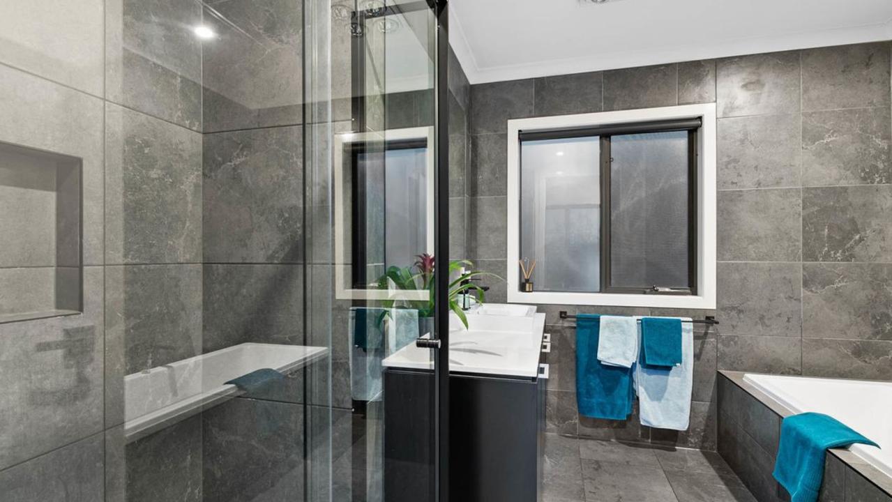 Floor-to-ceiling tiles and a spacious tub feature in the main bathroom.